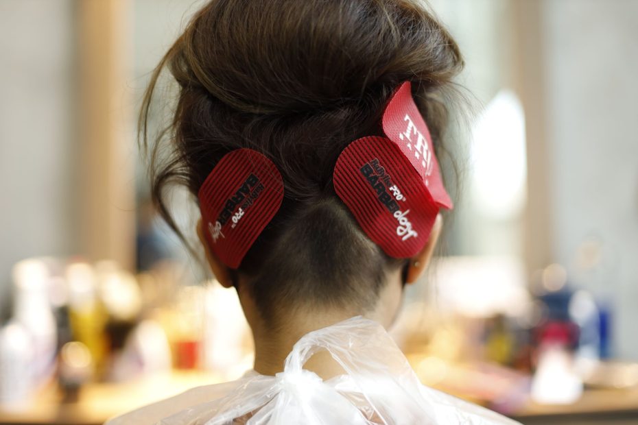 Back view of woman with brown hair and clips in salon setting.